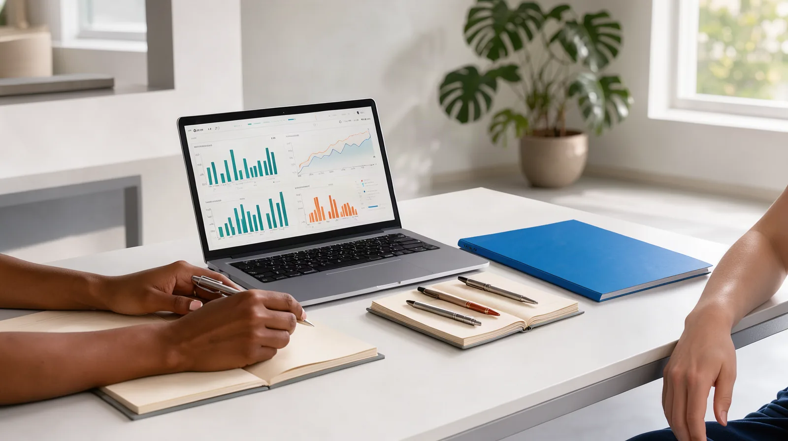 Como escolher uma agência de marketing em Jundiaí: 10 perguntas Foto de reunião em sala clara com notebook aberto mostrando gráficos, cadernos e canetas sobre a mesa